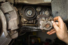 The Car Mechanic Holds In His Hand An Old Removed Car Engine Water Pump