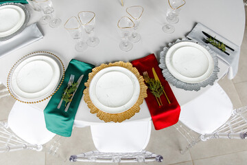 Wall Mural - Beautiful festive table setting with napkins of different colors. A luxurious dining set with cutlery, napkin, dishes and covered with a tablecloth in the restaurant. Gold plates and crystal glasses. 