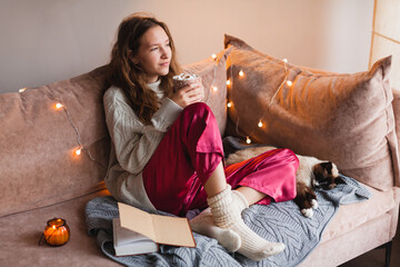 Wall Mural - Young woman with cat drinking warm coffee at home