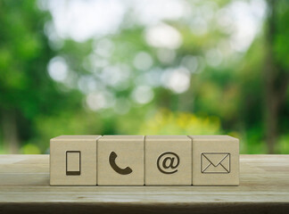 Poster - Mobile phone, telephone, email address, mail icon on wood block cubes on wooden table over blur green tree in park, Business customer service and support online concept