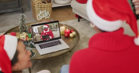 Poster - Diverse family with santa hats using laptop for christmas video call with santa on screen