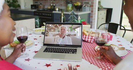 Poster - African american couple with wine using laptop for christmas video call with happy woman on screen