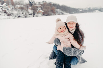 Canvas Print - Mom and daughter in winter. Happy family enjoy winter snowy day. They hug, laugh, have fun, ride in the snow and enjoy the winter snowy weather