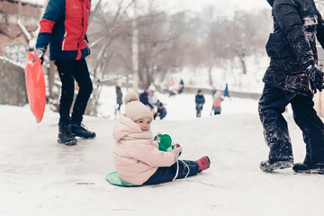 Canvas Print - 23.11.2018 Vinnitsa, Ukraine: little girl rides on an ice slide next to older children in the ordinary yard of high-rise buildings in the city where children spend winter fun