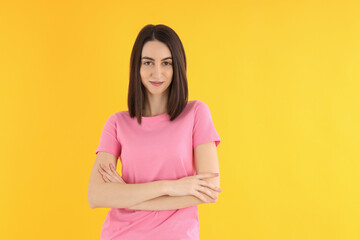 Wall Mural - Young attractive woman in t-shirt on yellow background