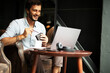 © Jelena - Handsome businessman working on laptop and sitting in cafe. Young student learning online.