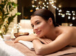 © Syda Productions - wellness, beauty and relaxation concept - young woman lying at spa or massage parlor over christmas lights on window background