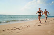 © Loginova - Healthy lifestyle. Jogging outdoors. Young man and woman is running on the sand beach.