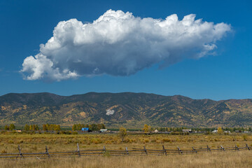 Wall Mural - Large white cloud over a hilly ridge