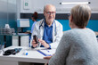 © DC Studio - Doctor giving bottle of pills with medicine to old patient at meeting appointment in cabinet. Physician showing jar with prescription treatment to sick woman at medical checkup visit.