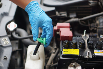 Mechanic's hand is opening bottle of water in car engine to Check auto car's coolant level. Concept : Checking and maintenance car service. 