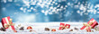 A Christmas website banner of Christmas presents, baubles and winter snow isolated against a wintery blue background with copy space.
