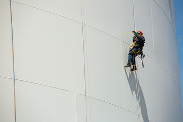 Wall Mural - Male workers control rope down height tank rope access inspection of thickness shell plate storage tank.