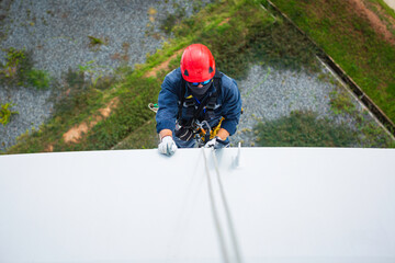 Wall Mural - Focus top view male worker down height tank roof rope access safety inspection of thickness storage tank.