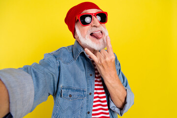 Wall Mural - Self-portrait of bearded elderly retired pensioner cheerful man showing horn fooling isolated over bright yellow color background