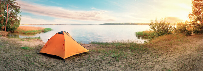Wall Mural - orange tourist tent on sandy shore of lake at sunrise