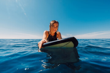Wall Mural - Portrait of surf girl on surfboard. Beautiful blonde woman look at camera on line up. Surfer in ocean