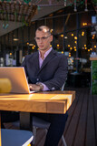 Fototapeta  - Young handsome businessman working on his laptop while sitting in a cafe