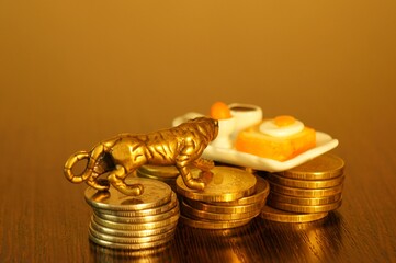 Wall Mural - A metal tiger and a toy tray with a cup of coffee and a sandwich on a stack of coins. Business concept.