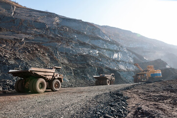 open cast mine dump trucks drive alone industrial area of iron ore quarry