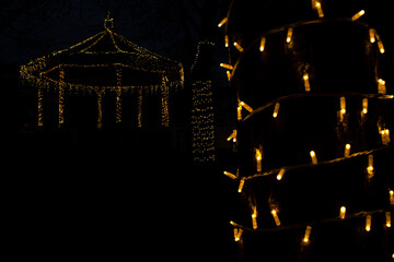 yellow lights at the tree and Bandstand decorated with christmas lights in the background