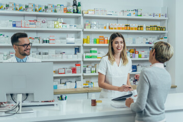 Wall Mural - Pharmacist giving prescription medications to smiling senior female customer