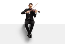 Full length shot of a violinist sitting on a blank panel and playing a violin