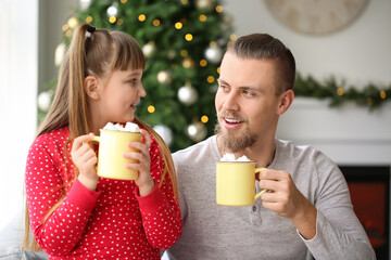 Wall Mural - Happy daughter and father with cups of hot cocoa at home