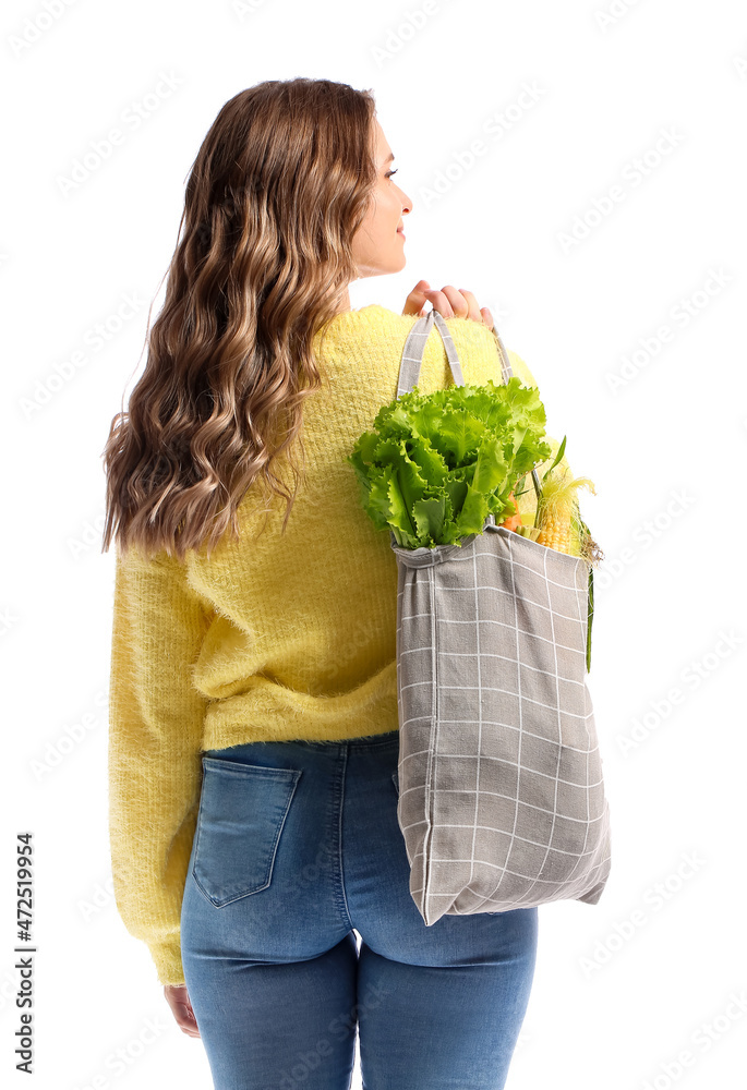 Young woman holding eco bag with fresh vegetables on white background
