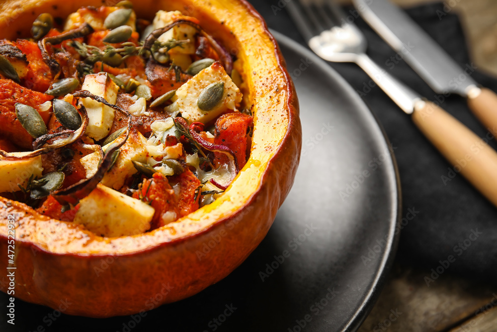 Plate with tasty stuffed pumpkin on wooden background, closeup