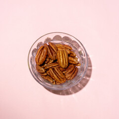 Wall Mural - Walnuts in a glass bowl on pink background