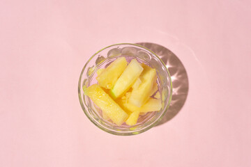 Wall Mural - Pineapple cut inside a glass container on a pink background