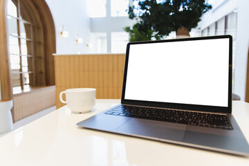Poster - Blank screen laptop computer modern man use room laptop with blank white desktop screen with coffee cup on wooden table in cafe