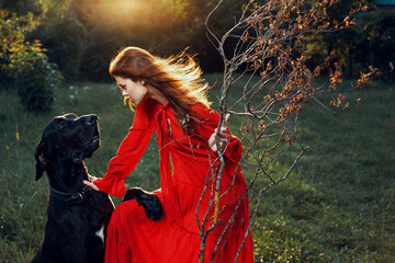 Wall Mural - pretty woman in red dress with dog outdoors posing glamor