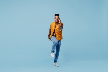 Full size body length jubilant young black man 20s years old wears yellow waistcoat shirt doing winner gesture celebrate clenching fists isolated on plain pastel light blue background studio portrait.