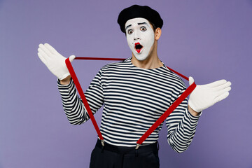 Wall Mural - Charismatic amazing amusing crazy dizzy young mime man with white face mask wears striped shirt beret holding suspenders with hands isolated on plain pastel light violet background studio portrait.