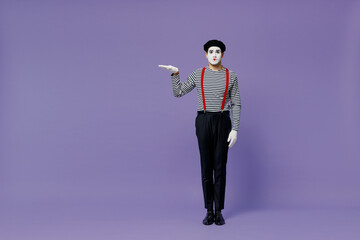 Wall Mural - Full size body length young mime man with white face mask wear striped shirt beret hold raised empty palm with copy space place mock up isolated plain pastel light violet background studio portrait