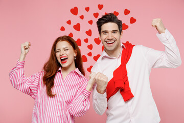 Wall Mural - Young couple two friends woman man in casual shirt look camera do winner gesture clench fist isolated on plain pastel pink background studio portrait. Valentine's Day birthday holiday party concept.