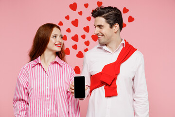 Canvas Print - Young fun couple two friends woman man in shirt use hold in hand mobile cell phone with blank screen workspace area isolated on plain pink background Valentine's Day birthday holiday party concept