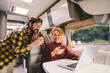 © simona - Adult couple enjoy work together using laptop computer sitting inside camper rv vehicle. Concept of nomad and alternative free job lifestyle. Modern man and woman people with technology