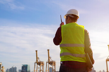 Engineers and crane.smiling dock worker holding radio and ship background