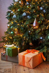 gifts in beautiful boxes of green and orange under the Christmas tree