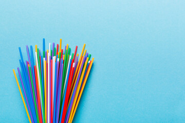 Heap of colorful plastic drinking straws on Colored background, flat lay. Copy Space for text