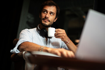 Handsome businessman working on laptop and sitting in cafe. Young student learning online.