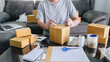 © Freedomz - Young entrepreneur SME man receive order client and working with packaging sort box delivery online market on purchase order and preparing package product, Small business parcel for shipment