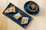 Fototapeta Uliczki - Homemade delicious sliced Apple Blueberry Pie on a black serving plate and a cup of black coffee on a wooden table. Top View