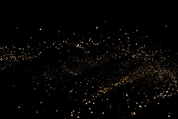 black festive background. abstract scattering of gold sparkles on black. holiday backdrop, selective