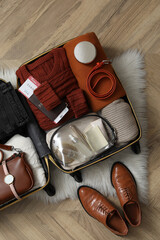 Wall Mural - Open suitcase with folded clothes, accessories and shoes on floor, flat lay