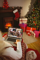 Poster - Santa claus making laptop christmas video call with smiling caucasian family in santa hats