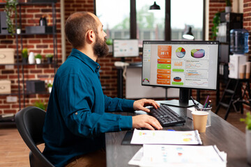 Poster - Businessman sitting at desk typing marketing strategy on computer keyboard analyzing data chart. Executive manager working at management presentation in startup office. Business concept
